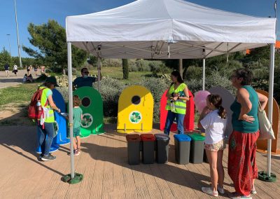Actividad educativa con contenedores de colores para enseñar reciclaje a alumnos de primaria en un colegio de Madrid.